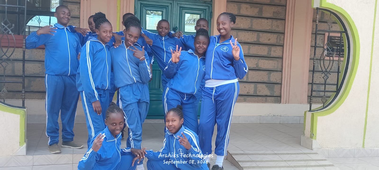 Learners in blue tracksuits outside the school